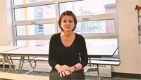 une femme assise à une table dans une salle de classe.